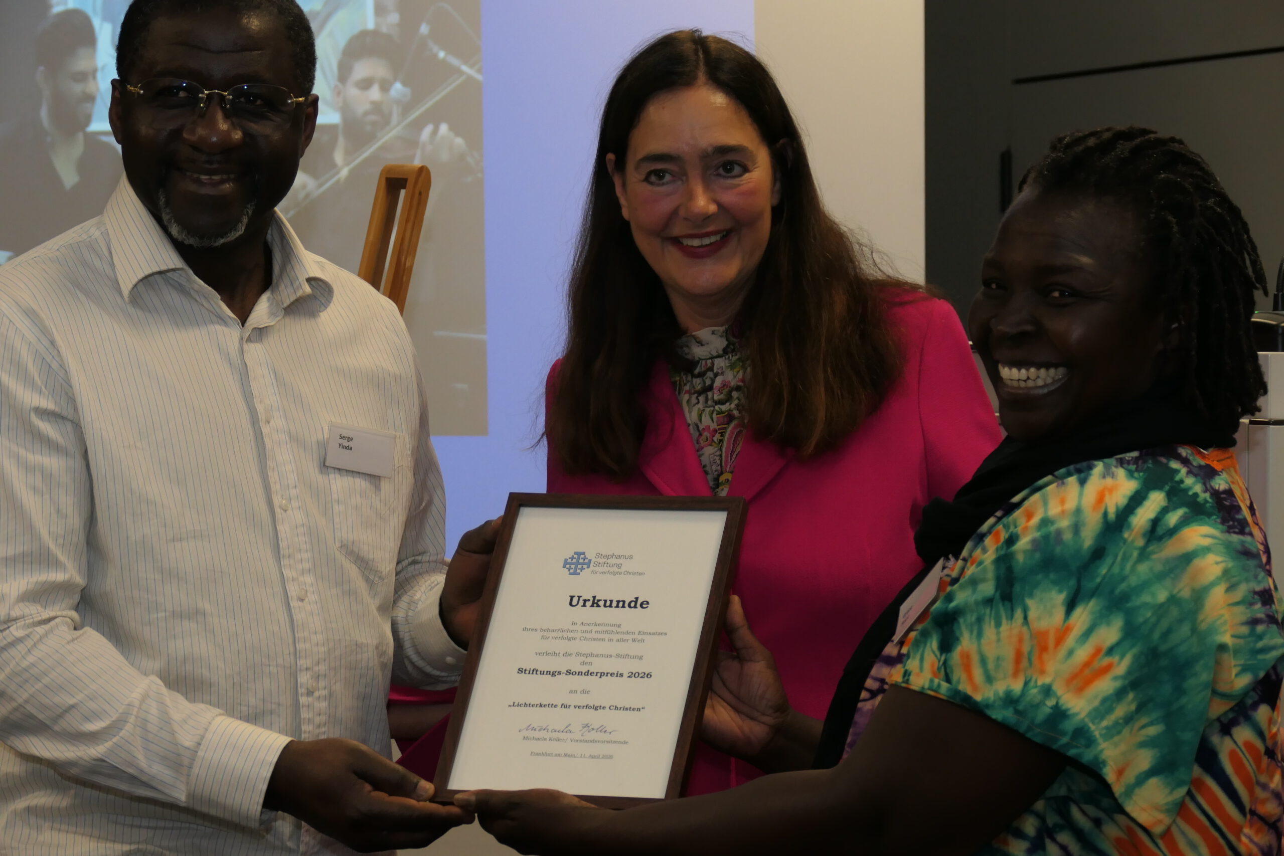 Grace Hope (rechts) und ihr Ehemann Serge (links) mit Stiftungsvorsitzender Michaela Koller (Mitte); Foto. W. Franke Grace Hope (rechts) und ihr Ehemann Serge (links) mit Stiftungsvorsitzender Michaela Koller (Mitte); Foto. W. Franke